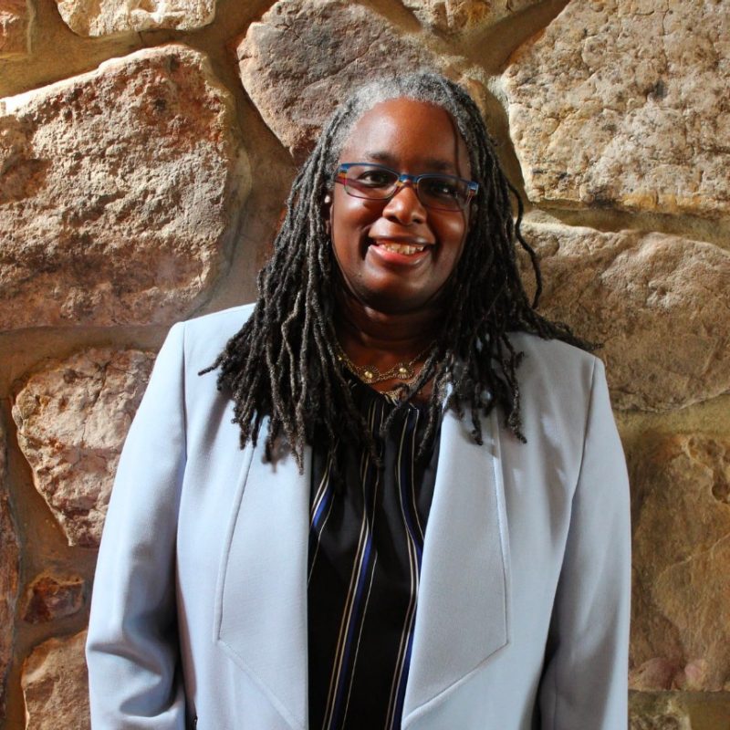 Vice President for Strategic Affairs and Diversity, Dr. Menah Pratt-Clarke in a blue suit standing in front of a stone wall. 